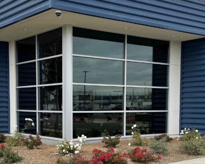 Modern glass office facade with precision-tinted windows reflecting coastal sky